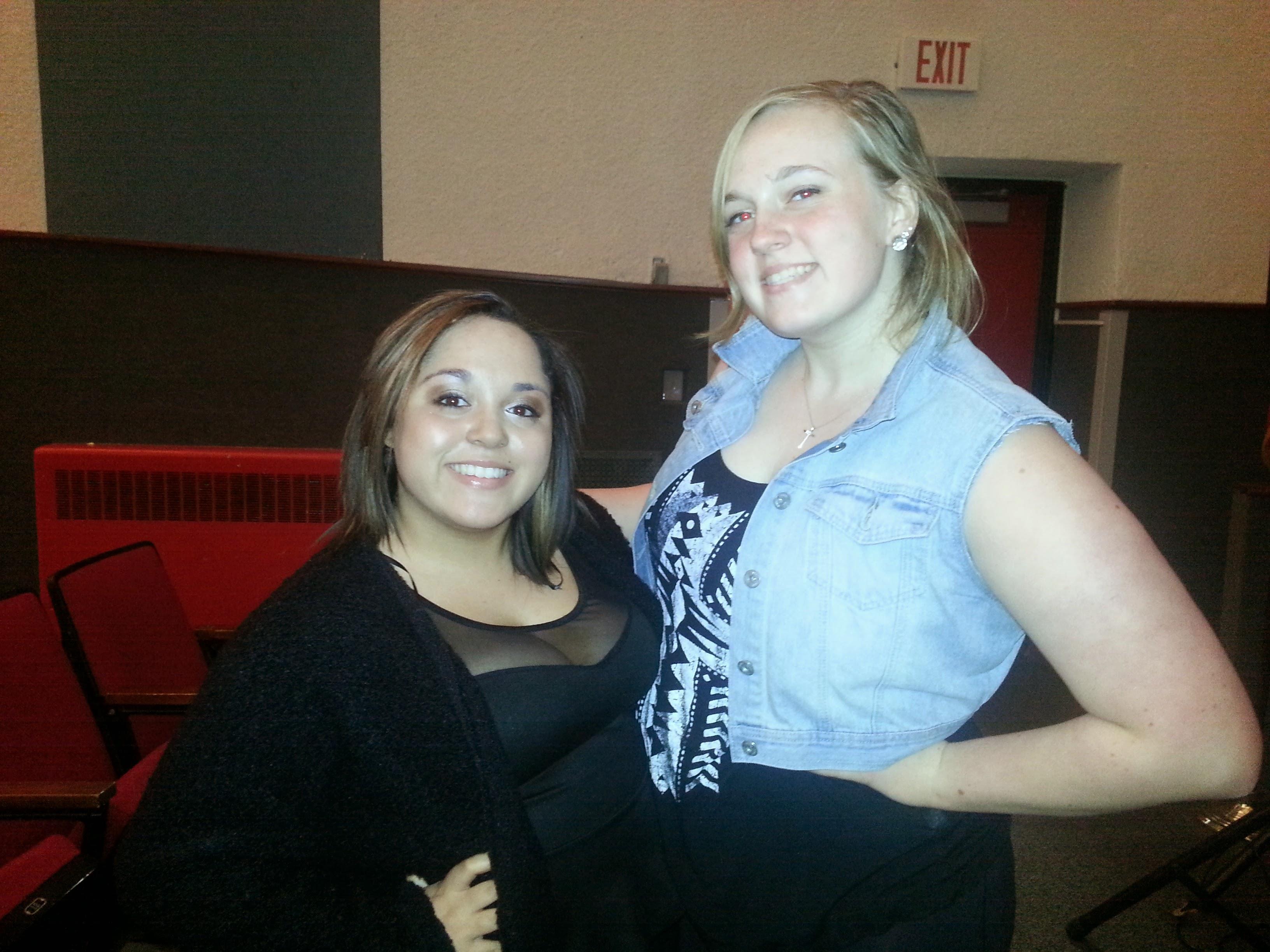 Two friends smile together, showing off their stylish outfits and enjoying each other's company.