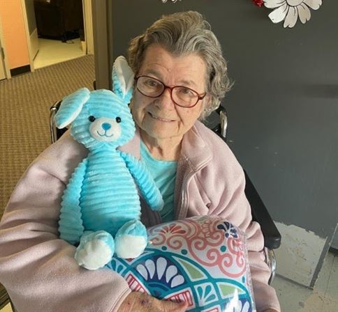 An old woman in a wheelchair holding a stuffed animal