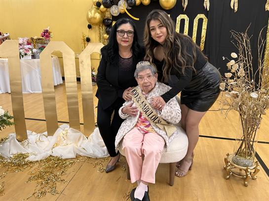 Three generations gather to celebrate a special birthday surrounded by elegant decorations.