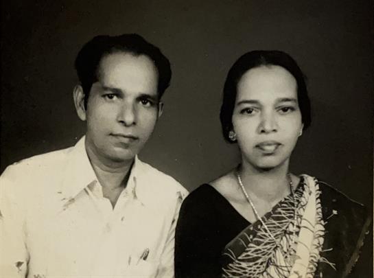 A couple in traditional outfits shares warmth and affection in a nostalgic setting.