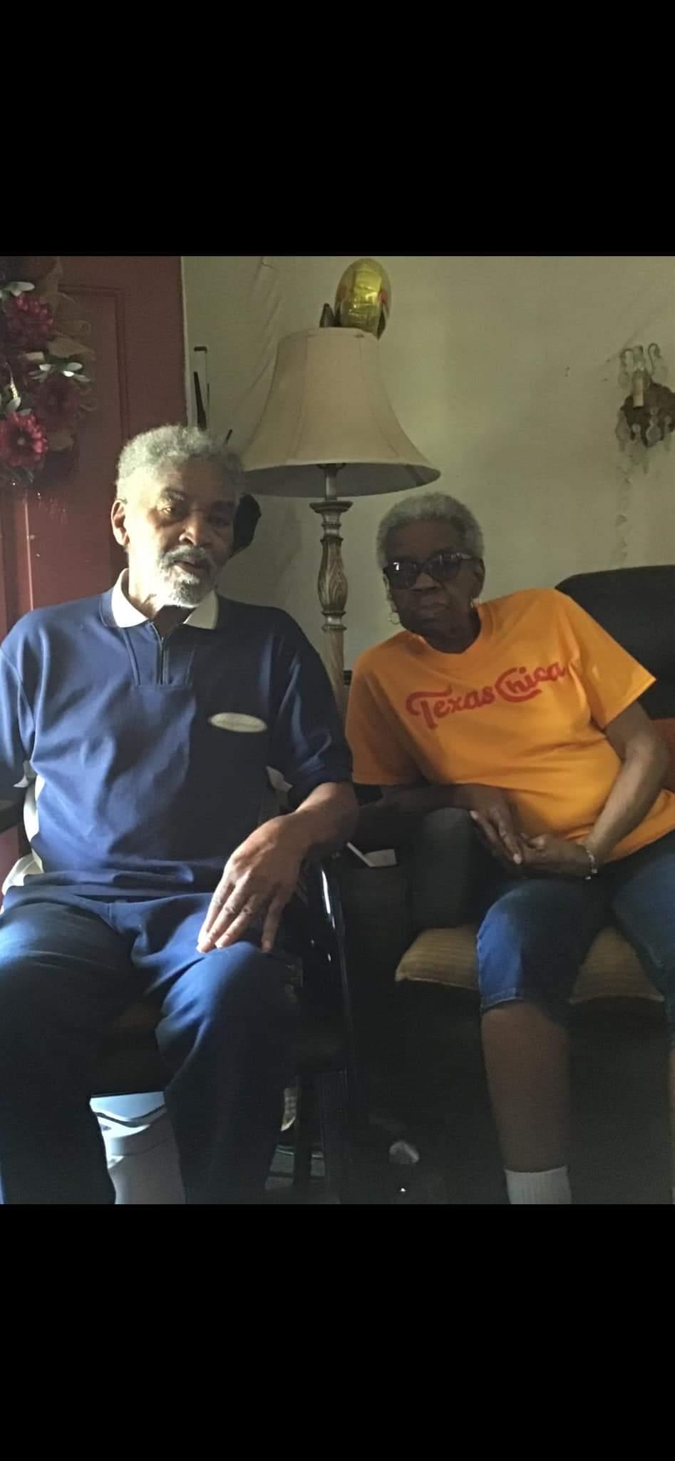 An elderly couple sits comfortably in their living room, sharing a warm moment of companionship.