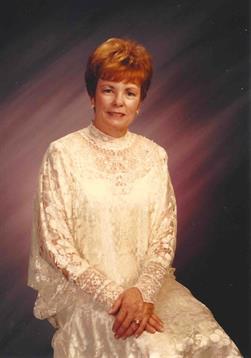 A woman in a shimmering white dress poses gracefully in a formal setting, her hair styled short.