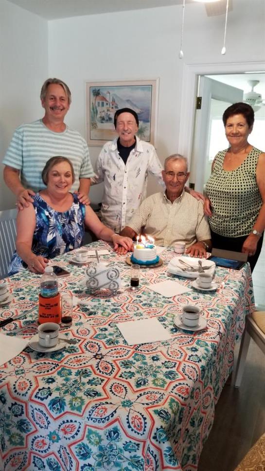 Family members gather together to celebrate a birthday with a cake and joyful expressions.