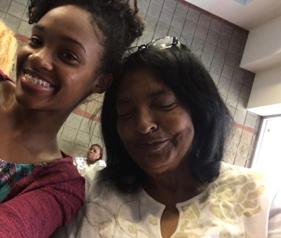 Two women smile together, enjoying a close and joyful moment in a communal space.
