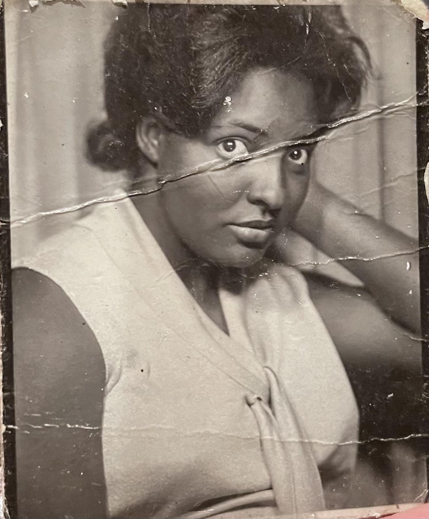 The woman poses with an engaging expression, showcasing her vintage attire and hairstyle.