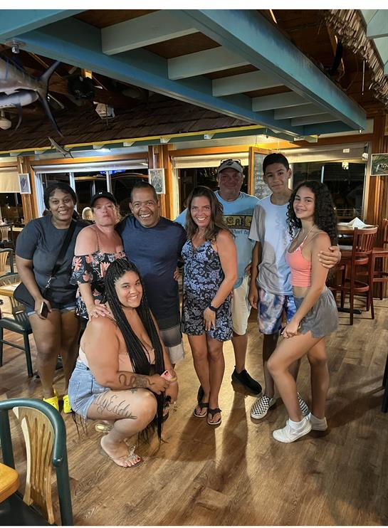 Friends and family enjoy time together in a restaurant, smiling and posing for a group picture.