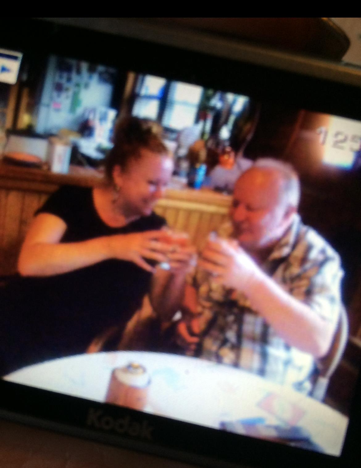 Two friends are smiling and toasting with drinks in a friendly atmosphere.
