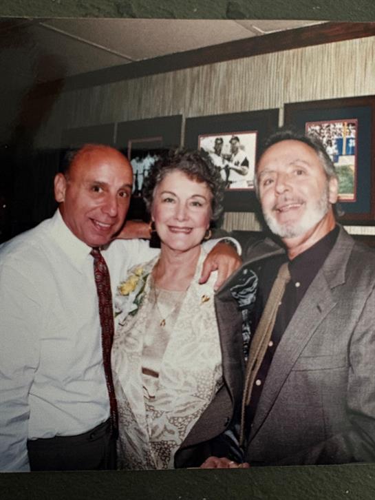Three friends gather in an indoor venue, joyfully celebrating a memorable event with smiles.