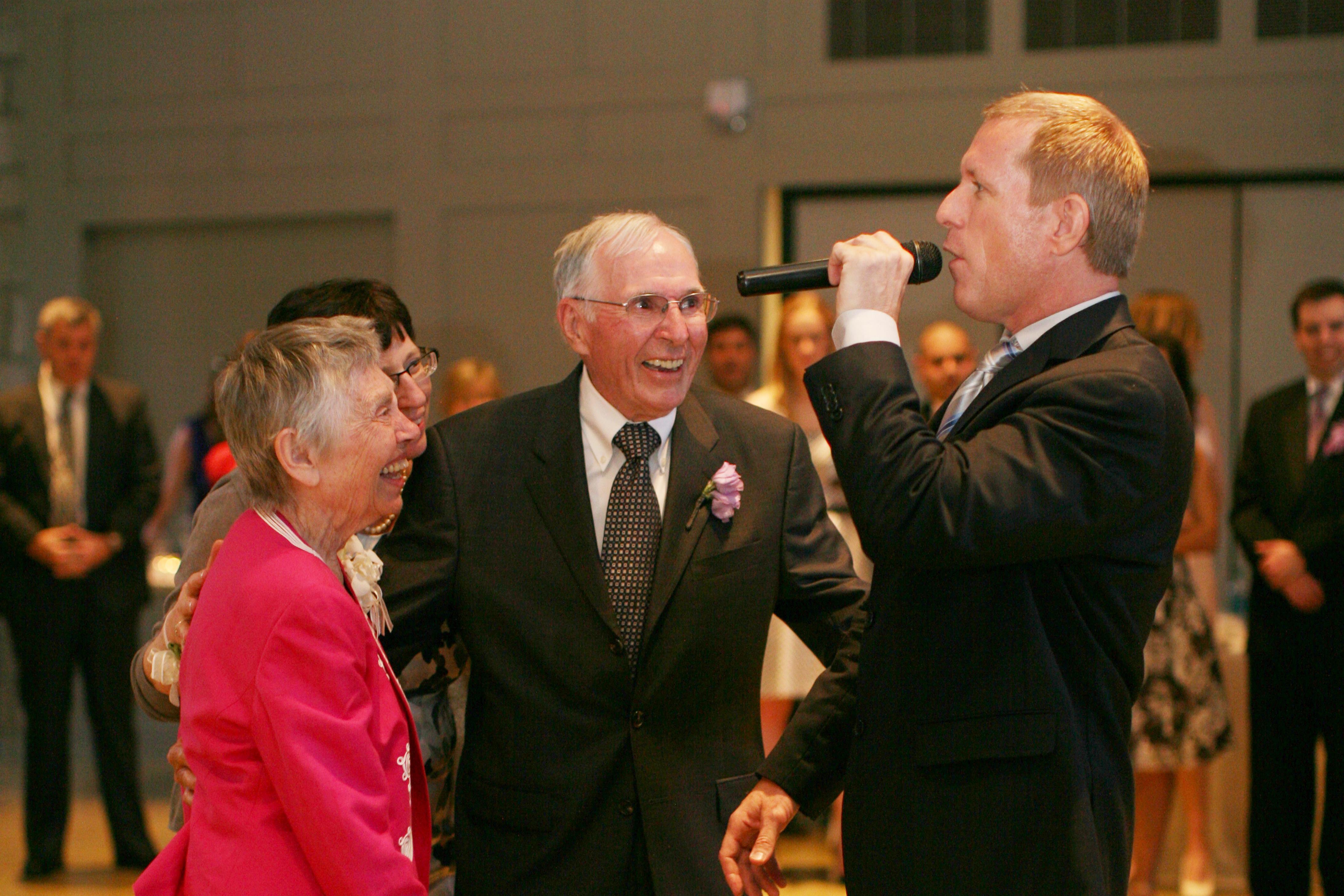 Seniors laugh and enjoy a lively performance at a community celebration during the evening.