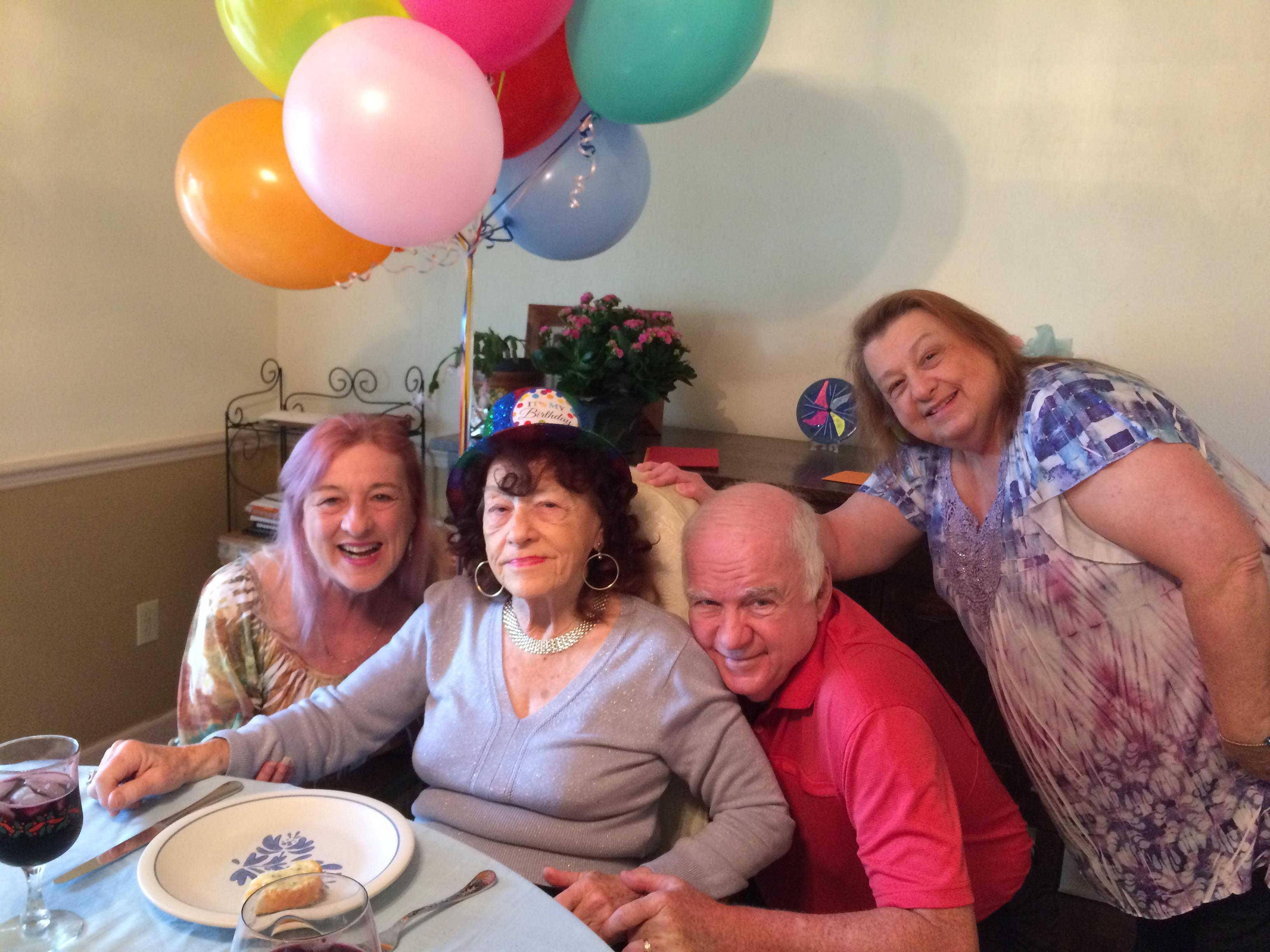 Friends and family gather together to celebrate a birthday with laughter, balloons, and food.