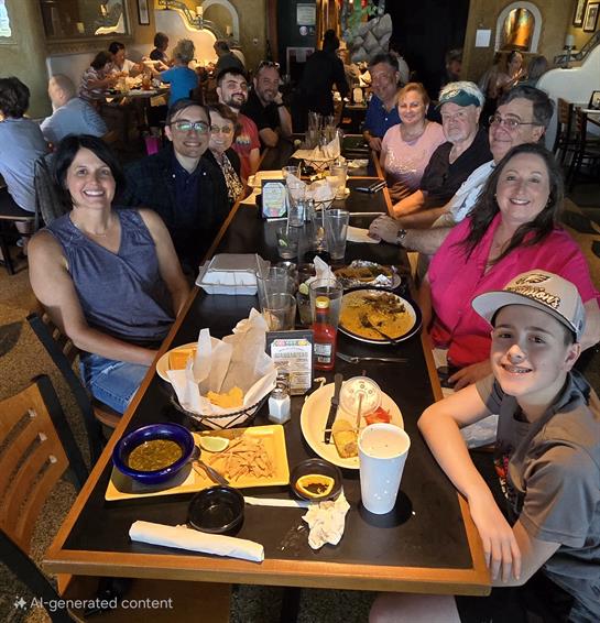 A lively group gathers around a large table filled with food, laughing and sharing stories.