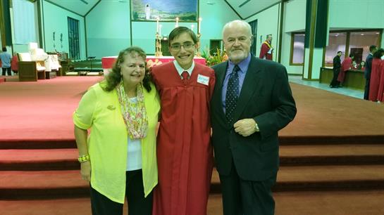 Graduates stand proudly with family members in a decorated venue celebrating an achievement.