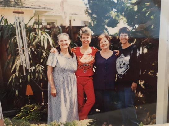 Friends gather in a garden, enjoying a sunny afternoon while posing for a group photo.