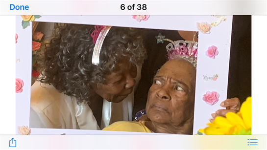 Two women share a heartfelt moment during a family celebration with floral decorations.