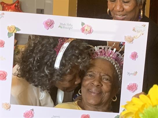 Family members gather around a grandmother, celebrating her birthday with love and fun.