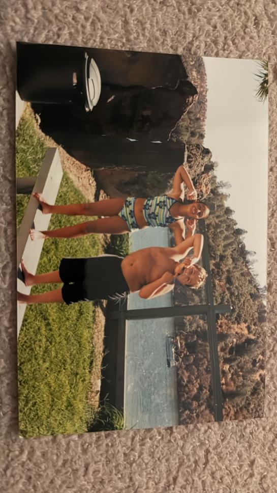 A couple poses playfully by the water in colorful swimwear, soaking up the sunshine outdoors.