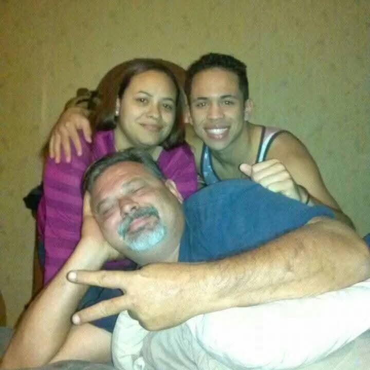 Three family members share a joyful moment, embracing and smiling warmly together.