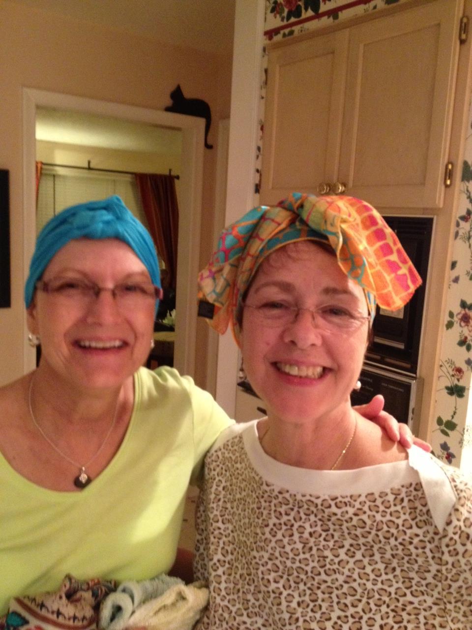 Two friends smile together in a warm, inviting kitchen adorned with floral decor.