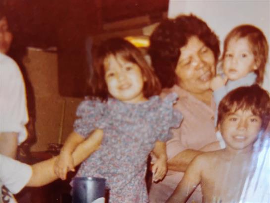Children smile and interact with their grandmother during a joyful family gathering indoors.