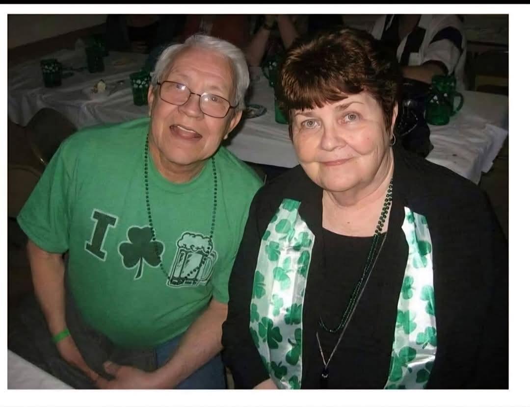 A happy couple dressed in St. Patrick's Day attire enjoys a cheerful moment at a celebration.