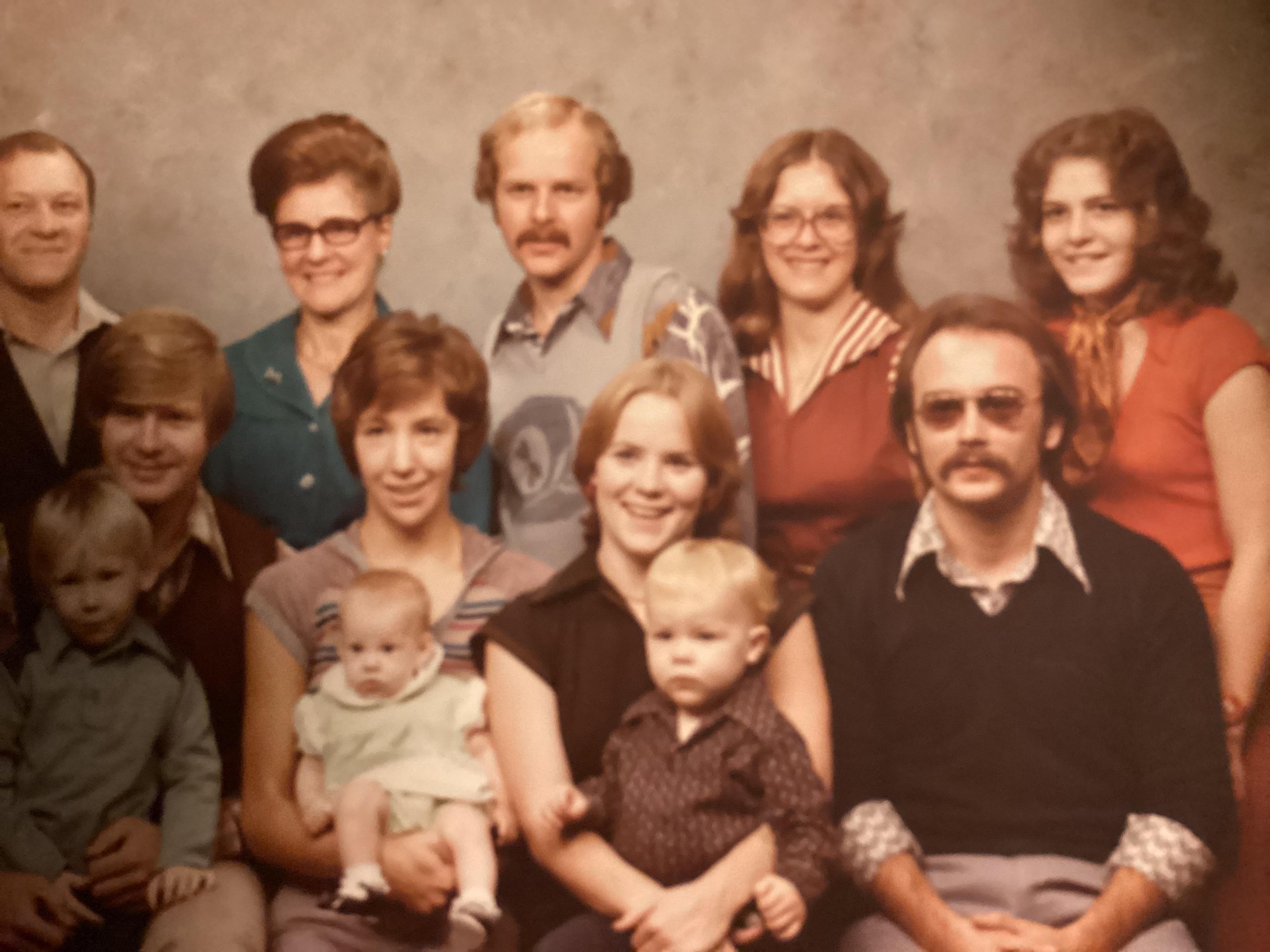 A large family celebrates together, showcasing multiple generations, smiling and posing happily.