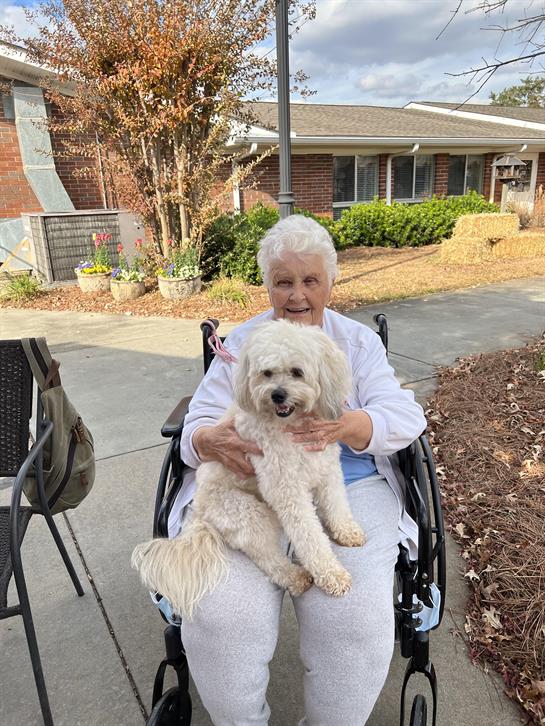 An old woman in a wheelchair holding a dog