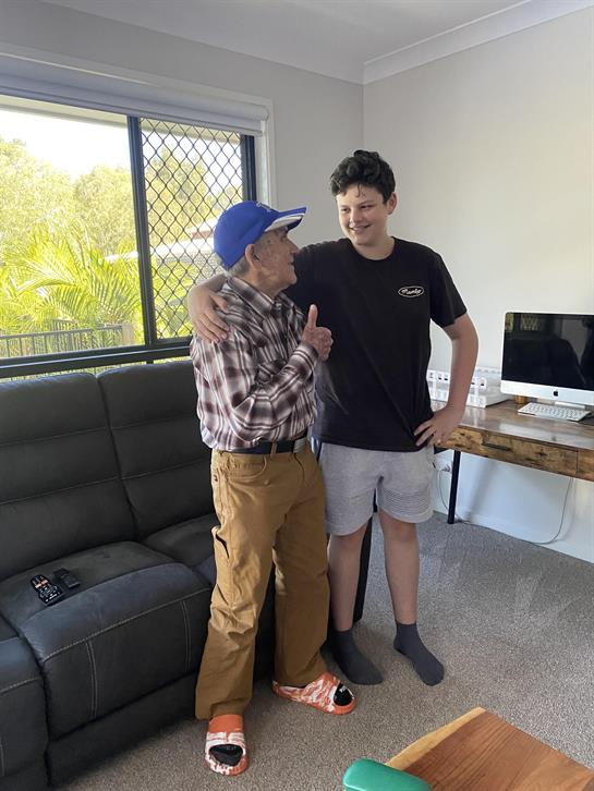 An elderly man in casual attire interacts playfully with a young boy in a living room setting.