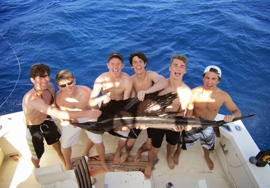 Friends proudly show off their big catch while enjoying a sunny day on a boat.