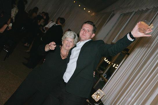 Two individuals enjoy a lively moment, dancing and celebrating at a stylish event indoors.