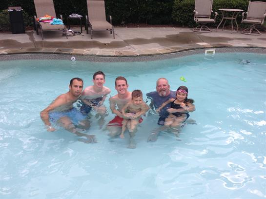 A group of six people enjoys a fun day at the pool, splashing and playing together in the water.