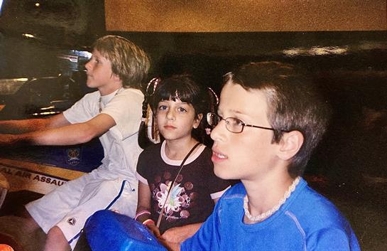 Three children are engaged in an exciting activity at an indoor amusement arcade.