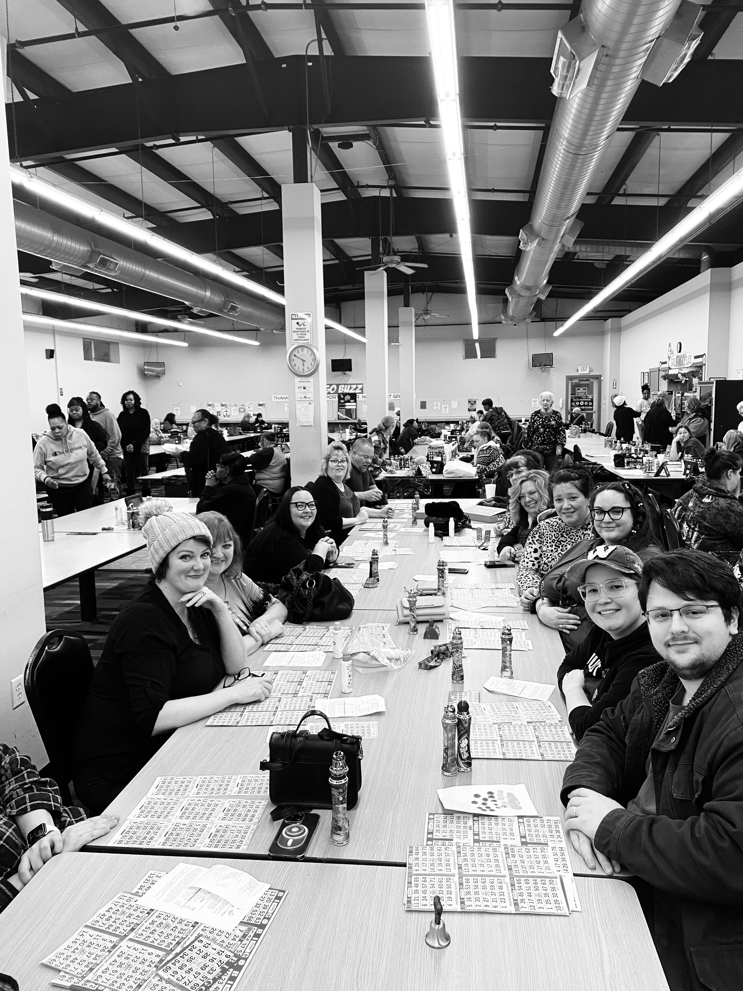 Participants gather around tables, eagerly playing bingo in a bustling community center.
