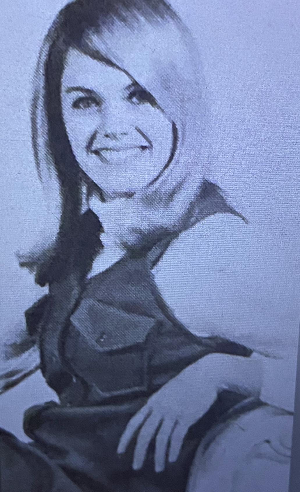 A woman with wavy hair smiles confidently, dressed in a sleeveless top, radiating joy.