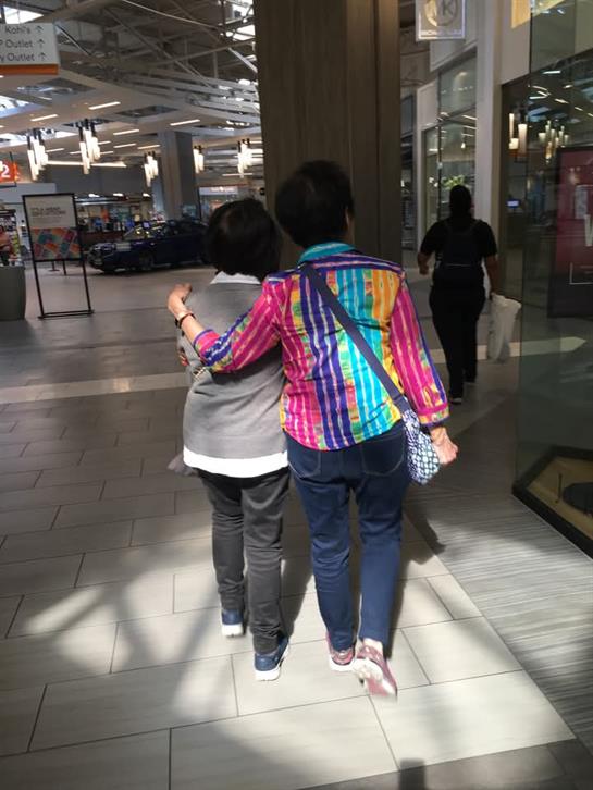 Two individuals stroll through a spacious shopping mall, enjoying their time together.