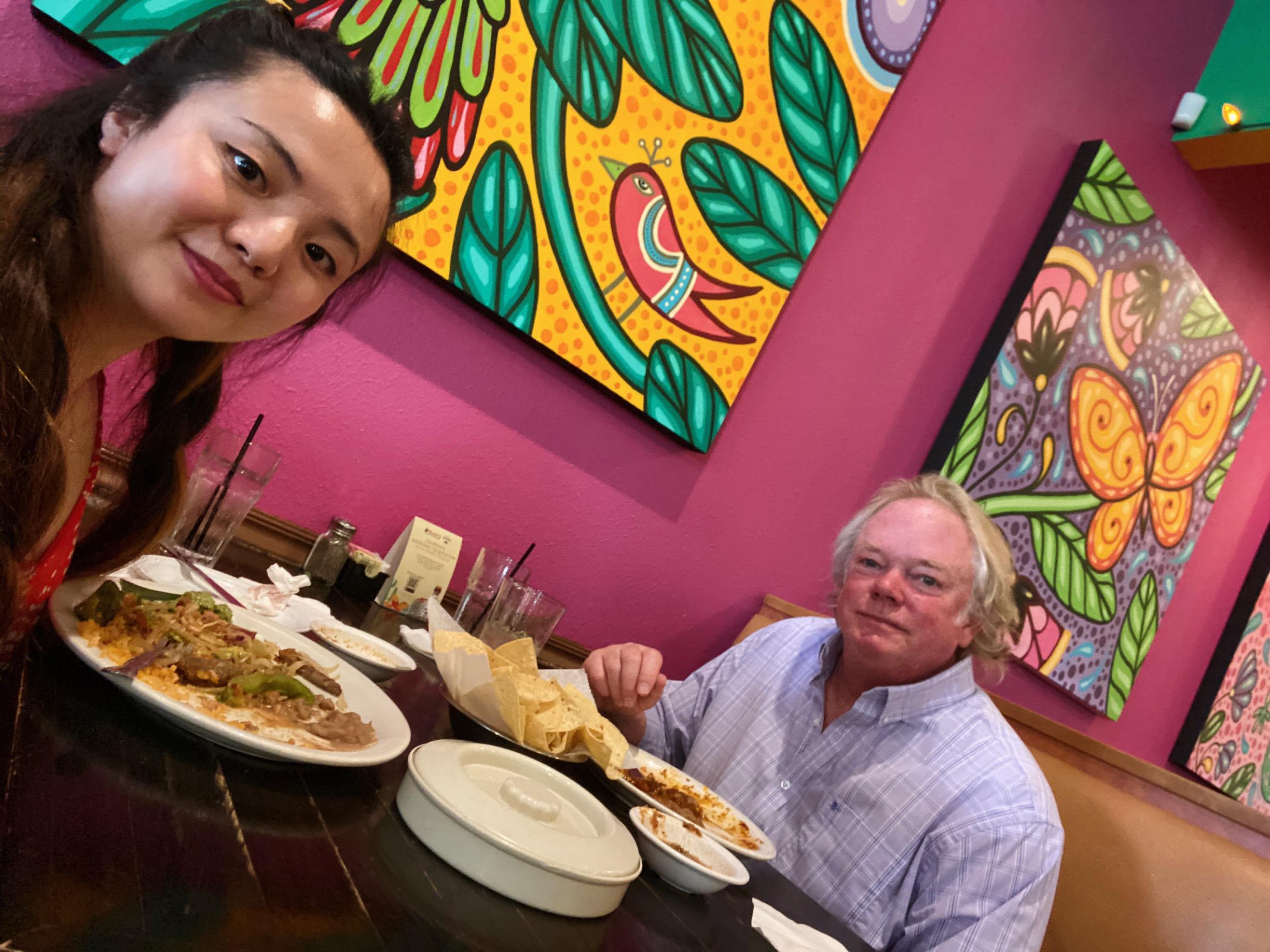 Friends share a meal in a lively restaurant adorned with bright and colorful decorations.
