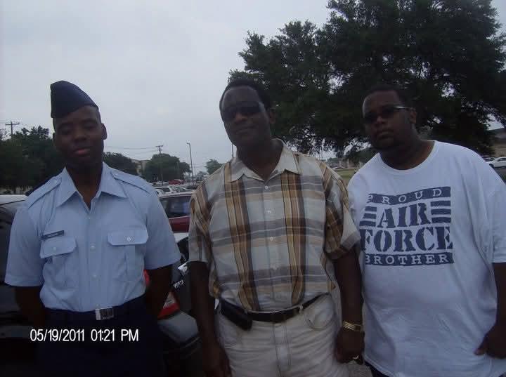 Three men stand together, enjoying a leisurely moment in a parking lot during May.