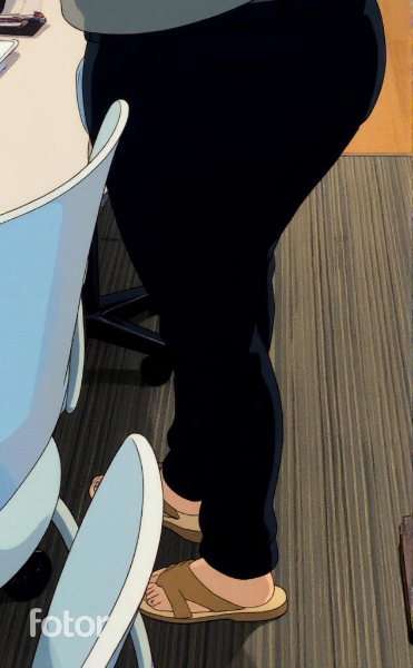 Individual in a blue office chair watches a colleague standing, engaged in work at a desk area.