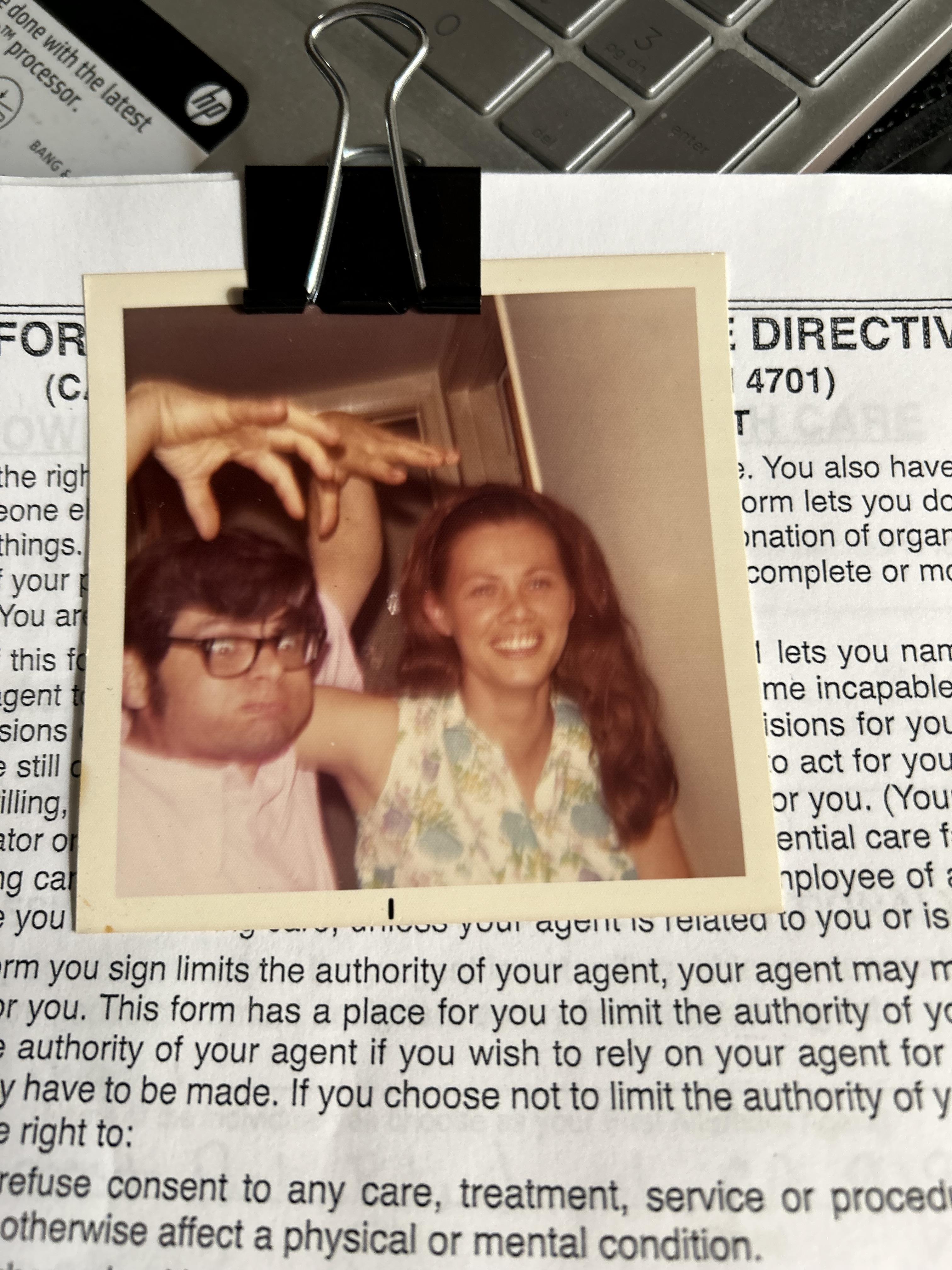 Two friends share a lighthearted moment with playful gestures, laughing together indoors.