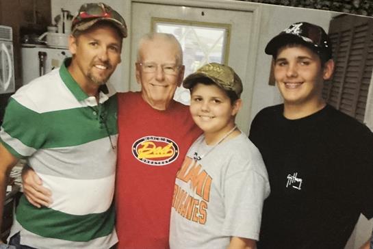 Four family members smile warmly in a kitchen during a relaxed afternoon gathering.
