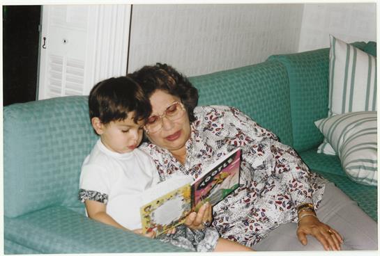 A grandmother reads a colorful book to her attentive grandchild, creating a bonding moment.