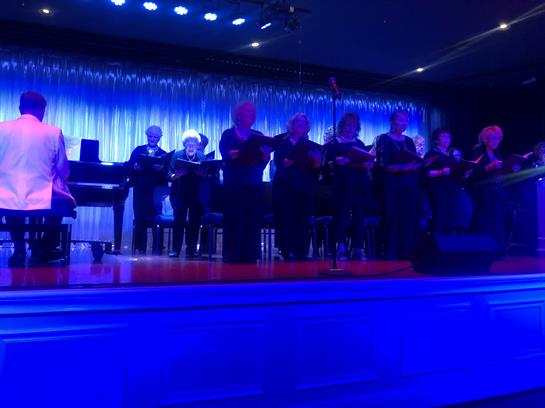 A vocal group performs joyfully while a pianist plays during a lively evening event.