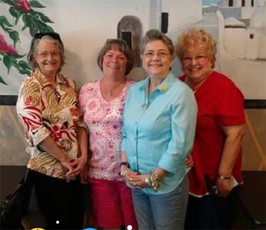 Four friends smile and pose together inside a vibrant restaurant while enjoying their time.