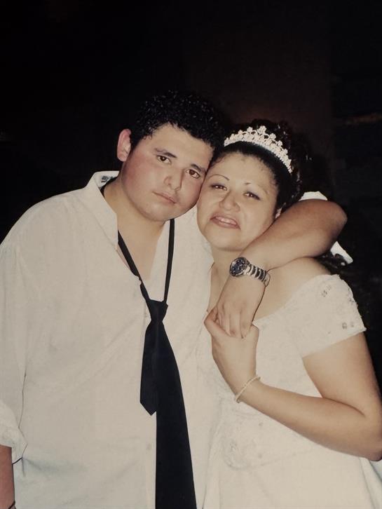 A couple dressed in formal attire share a heartfelt embrace during a nighttime event.