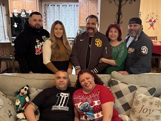 A family smiles together in a cozy living room, enjoying holiday moments.