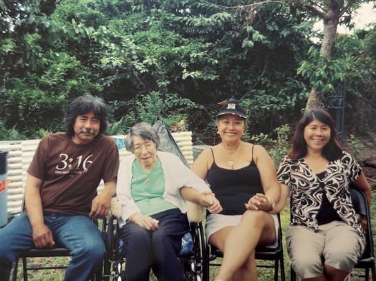 Four family members enjoy a sunny afternoon in the garden, holding hands and sharing smiles.