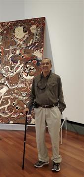 An elderly man enjoys a detailed mural while standing in an art gallery during an event.