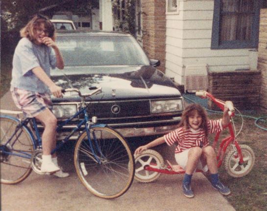 Two people on bicycles and a car