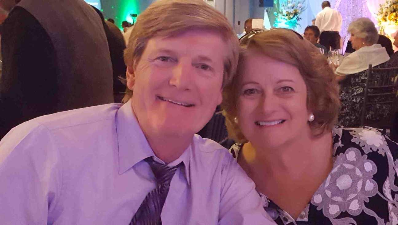 Couple smiles happily while seated at a decorated table during a festive evening gathering.