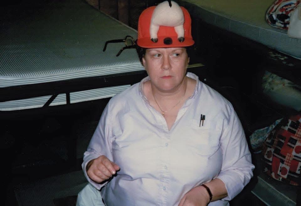 A woman sits wearing a playful hat, engaged in conversation with others in a relaxed atmosphere.