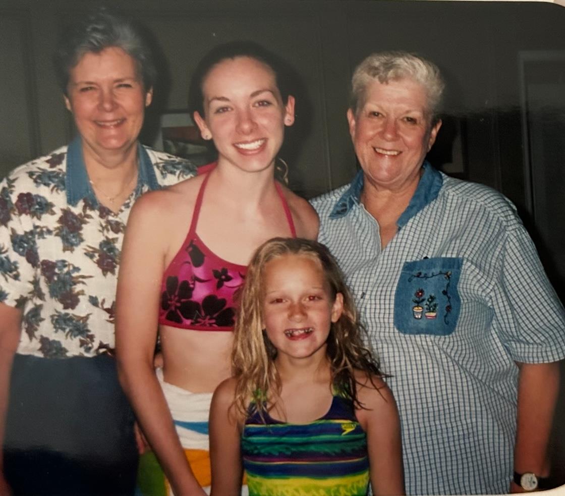 Four women of different ages smile together, celebrating summer in vibrant swimwear.